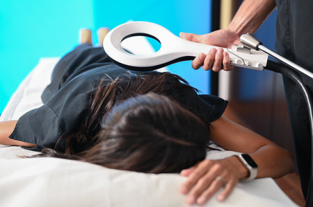 Physiotherapist applying innovative physiotherapy technology on a patient lying on a medical bedの写真素材