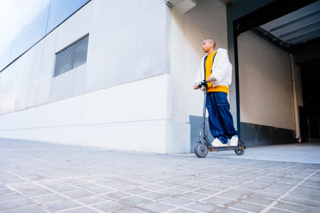 Young man riding an electric scooter near a modern building