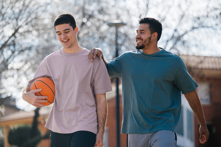 Two happy multi-ethnic young men walking together after a basketball game in the cityの写真素材