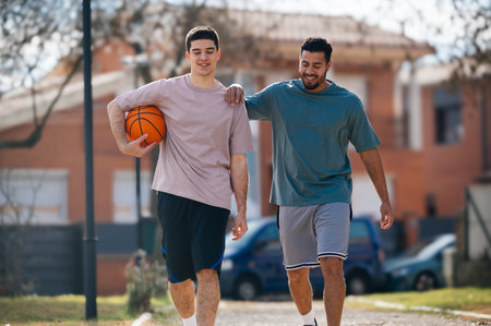 Two happy basketball players walking and talking after a street basketball matchの写真素材