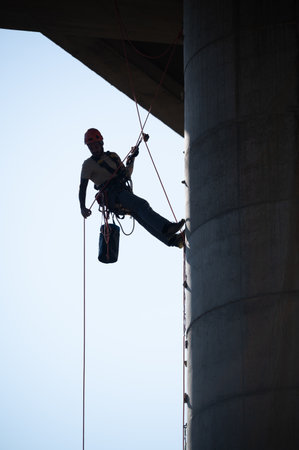 Industrial climber checking the safety on concrete bridge pillar using rope access techniquesの写真素材