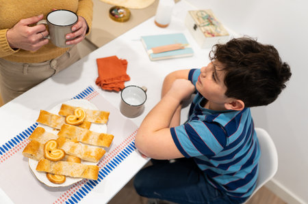 Mother and son enjoying a snack while studying together at the kitchen tableの写真素材
