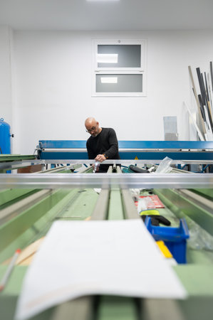 Carpenter assembling an aluminum window frame in his workshop, using professional tools and precisionの写真素材
