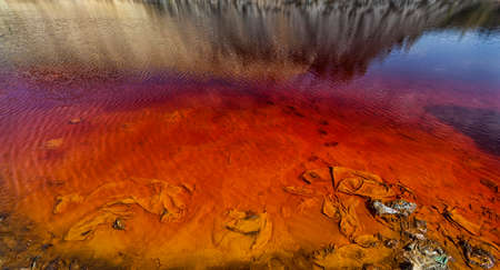 Red artificial lake and hills as a result of mining and production of copperの写真素材