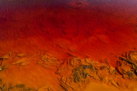 Red artificial lake and hills as a result of mining and production of copperの写真素材