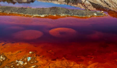 Red artificial lake and hills as a result of mining and production of copperの写真素材