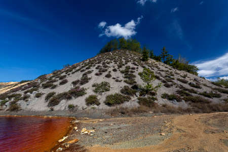 Red artificial lake and hills as a result of mining and production of copper