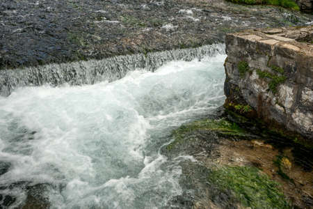 Clear mountain river in a decorated river bed with fishesの写真素材