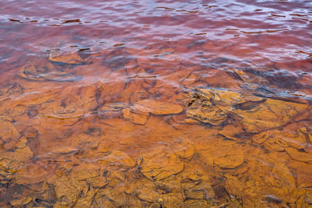 Red artificial lake and hills as a result of mining and production of copperの写真素材