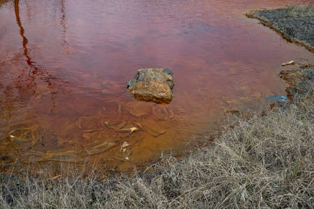 Red artificial lake and hills as a result of mining and production of copperの写真素材