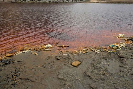 Red artificial lake and hills as a result of mining and production of copperの写真素材