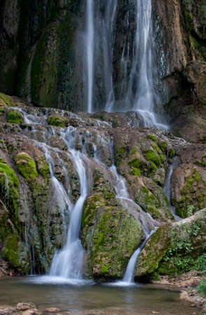 Waterfall on a mountain stream with rocks covered with moss