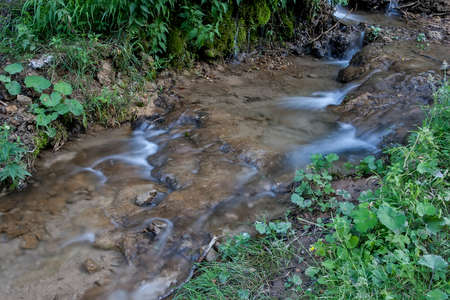 Waterfall on a mountain stream with rocks covered with moss