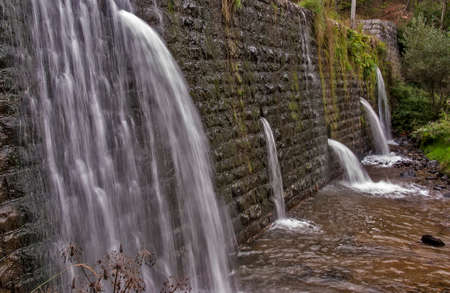 Square concrete blocks dam on the river with holes for drain waterの写真素材