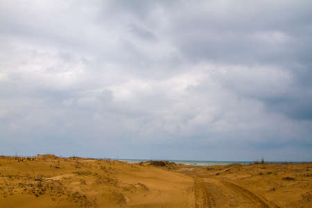 Photo of a sandy road to beach.  There is only sand until the sea. Tyre trails are also visible....