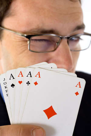 Winking man showing four aces and joker cards in foreground.