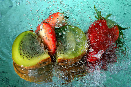 Slices of kiwi and strawberry with water drops の写真素材