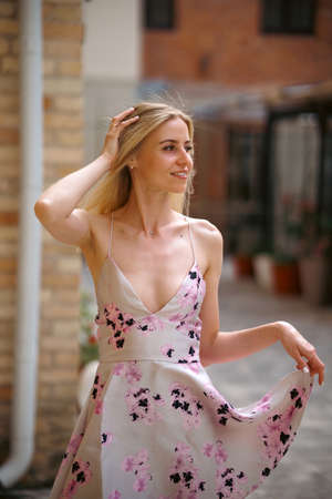 Stylish young woman in a short summer dress walking in the city on a hot day.の写真素材