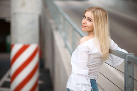 Beautiful blonde fashionable sexy tourist girl walking in city street. Woman looking at camera outdoors wearing trendy white t-shirt, denim jean short skirt.の写真素材