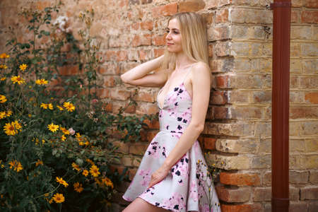 Fresh portrait pretty woman with sexy lips with make-up in pink dress with amazing yellow flowers. Gorgeous glamorous girl looks at flowers. beauty lady.の写真素材