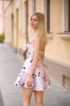 Stylish young woman in a short summer dress walking in the city on a hot day.の写真素材