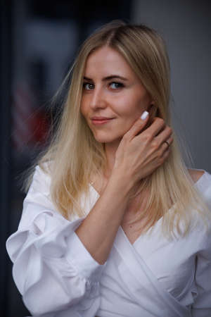 Beautiful blonde fashionable sexy tourist girl walking in city street. Woman looking at camera outdoors wearing trendy white t-shirt, denim jean short skirt.の写真素材
