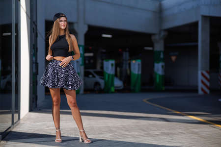 Portrait of a pretty attractive sexy young woman with natural makeup with beautiful eyes in a fashionable denim jacket in a black stylish dress. american girl walking in cityの写真素材