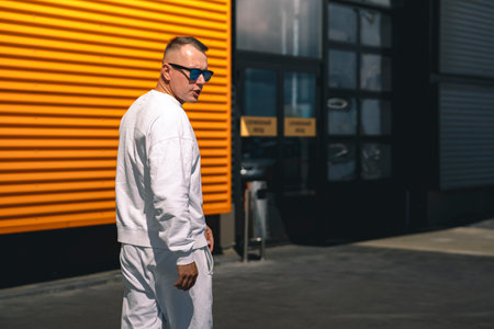 Portrait of a young guy walking around the city in a white suit and sunglassesの写真素材