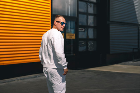 Portrait of a young guy walking around the city in a white suit and sunglassesの写真素材