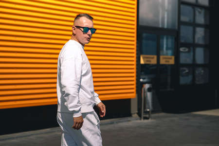 Portrait of a young guy walking around the city in a white suit and sunglassesの写真素材