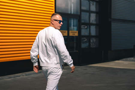 Portrait of a young guy walking around the city in a white suit and sunglassesの写真素材