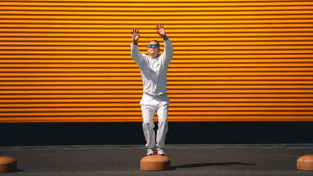 Portrait of a young guy walking around the city in a white suit and sunglasses