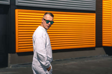 Portrait of a young guy walking around the city in a white suit and sunglassesの写真素材
