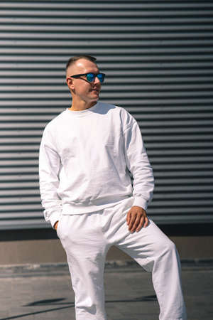 Portrait of a young guy walking around the city in a white suit and sunglassesの写真素材