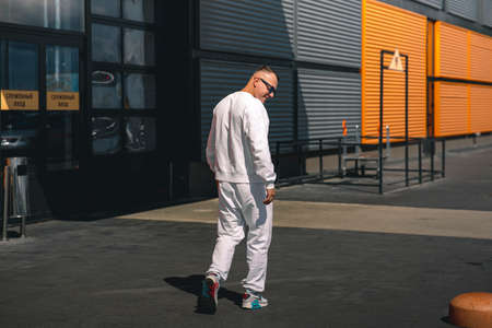 Portrait of a young guy walking around the city in a white suit and sunglassesの写真素材