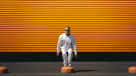Portrait of a young guy walking around the city in a white suit and sunglassesの写真素材
