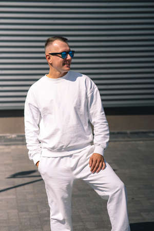 Portrait of a young guy walking around the city in a white suit and sunglassesの写真素材