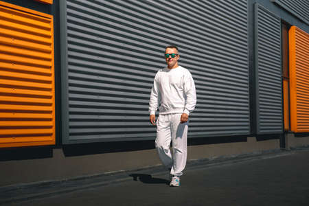 Portrait of a young guy walking around the city in a white suit and sunglassesの写真素材