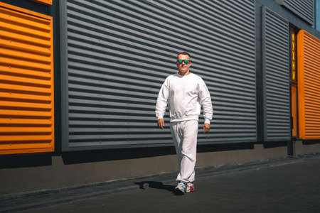 Portrait of a young guy walking around the city in a white suit and sunglassesの写真素材