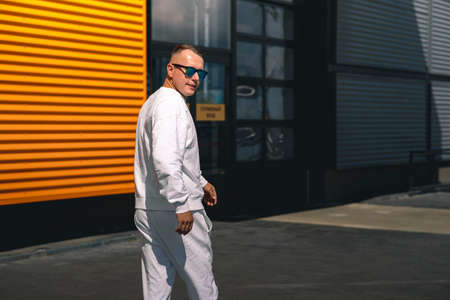 Portrait of a young guy walking around the city in a white suit and sunglassesの写真素材