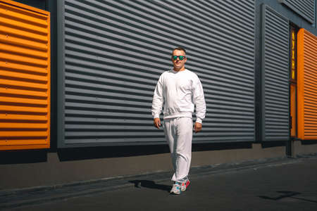 Portrait of a young guy walking around the city in a white suit and sunglassesの写真素材