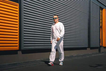 Portrait of a young guy walking around the city in a white suit and sunglassesの写真素材