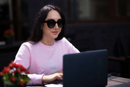 Woman working with a laptop in a cafe. Business lady combines rest with work.の写真素材
