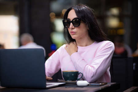 Woman working with a laptop in a cafe. Business lady combines rest with work.の写真素材
