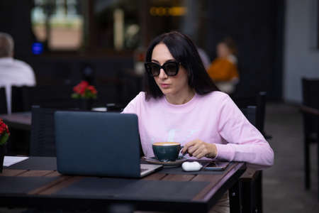 Woman working with a laptop in a cafe. Business lady combines rest with work.の写真素材
