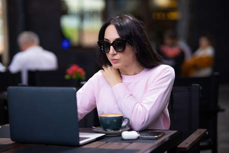 Woman working with a laptop in a cafe. Business lady combines rest with work.の写真素材