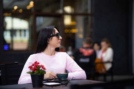 Portrait pretty trendy young brunette woman in stylish clothing with vintage cup in cafe. Elegant cute girl fashion model enjoys coffee break indoors. Morning for caffeine lovers.の写真素材