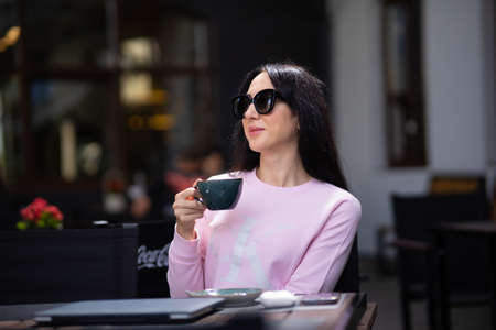 Portrait pretty trendy young brunette woman in stylish clothing with vintage cup in cafe. Elegant cute girl fashion model enjoys coffee break indoors. Morning for caffeine lovers.の写真素材