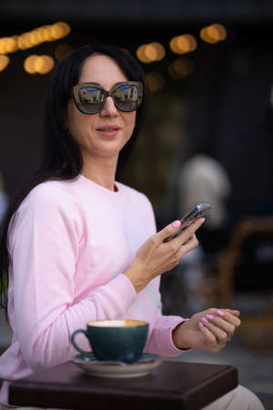 Portrait pretty trendy young brunette woman in stylish clothing with vintage cup in cafe. Elegant cute girl fashion model enjoys coffee break indoors. Morning for caffeine lovers.の写真素材