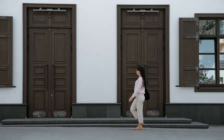 Gorgeous young woman in fashion clothes walk at the street. Attractive girl model in casual outfit walk on city street near vintage building. side view.の写真素材